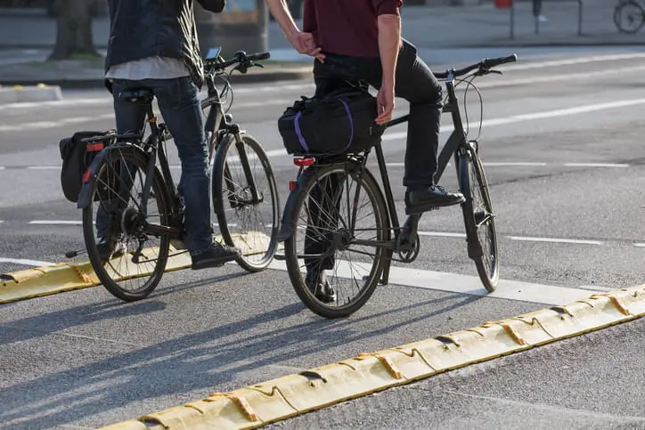 two cyclists wait in a protected bike lane