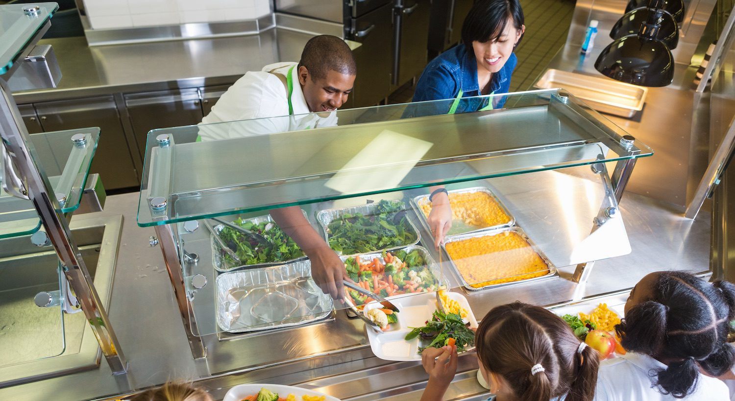 Cafeteria workers provide healthy food options in a public cafeteria.