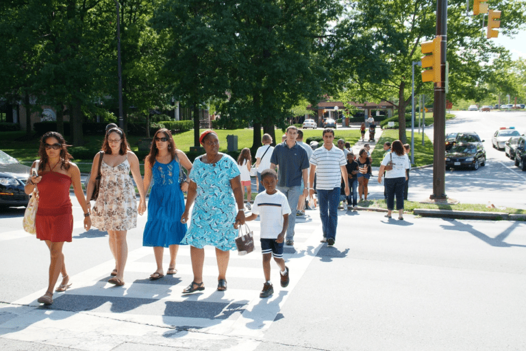 A group of people cross the street in a clearly marked crosswalk in a busy city